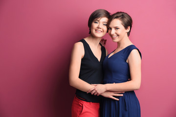 Young lesbian couple on color background