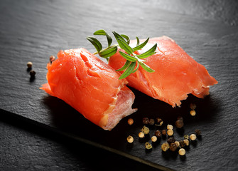 Roll slice of salmon, basil on black slate