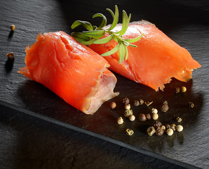 Roll slice of salmon, basil on black slate