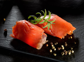 Roll slice of salmon, basil on black slate