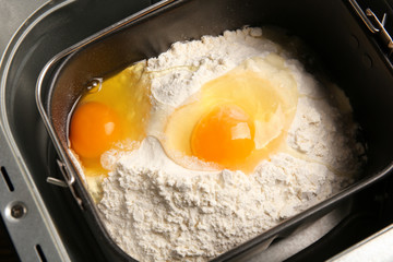 Modern bread machine with flour and raw eggs, closeup
