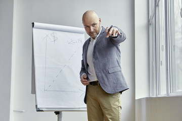 Fototapeta premium Bald Businessman Poiting at Something With a Marker