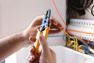 Young electrician skinning a wire in light room