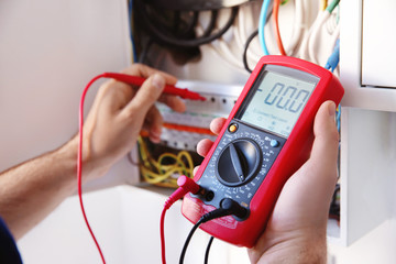Young electrician measuring voltage in distribution board