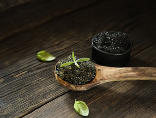 Black caviar in a wooden spoon on a wooden background