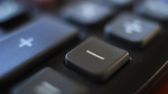 Subtraction on a calculator device. Finger press on minus button calculator