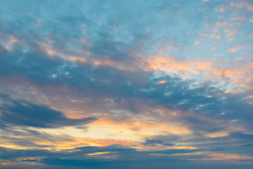 Naklejka na ściany i meble Clouds on a blue sky illuminated by the sun at sunset.