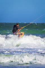 Fototapeta premium Young atletic man riding kite surf on a sea