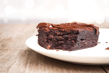 Homemade brownies on white plate. With chocolate fudge topping. Over wooden background.