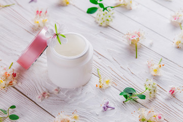 Obraz na płótnie Canvas Jar with cream surrounded with flowers