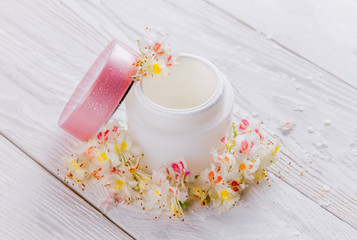 Fototapeta na wymiar Jar with cream surrounded with flowers