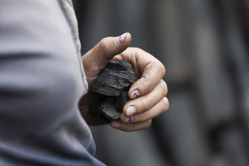 Obraz premium Closeup on hand with small piece of coal