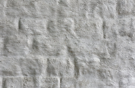 Ancient white brick wall with a thick layer of plaster