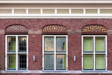 Front beautiful old flat house facade pattern from red brick with white window frame. Vintage building. Netherlands