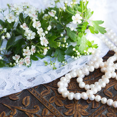 Hawthorn blossom with lace and pearls on carved wood table