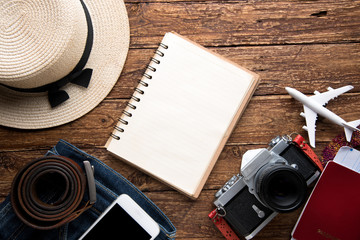 travel concept with notebook and camera on wooden table background