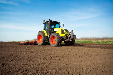 Obraz premium Farmer in tractor preparing land with seedbed cultivator