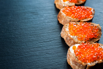 Red caviar on slate background.
