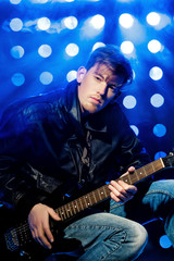 young attractive rock musician playing electric guitar and singing. Rock star on background of spotlights