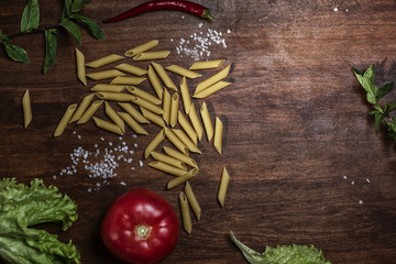 Pasta and other products on the table. Pepper, tomato, salt, penne. Top. Frame for text.