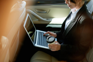 Smiling businesswoman in a car with coffee