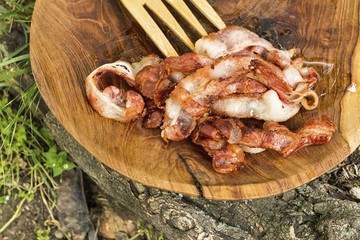Stack of fried bacon strips in wooden bowl. Macro shot.