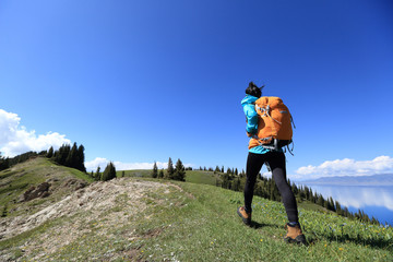 Fototapeta na wymiar Successful woman backpacker hiking on mountain peak