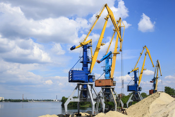 Cranes in the river port near the sand mound