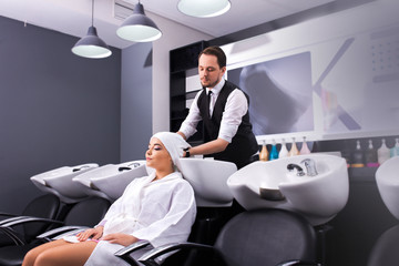The attractive male master dries the girl's hair with towel in the beauty salon