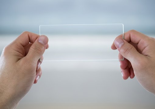 Hands With Glass Device Against Blurry Beach