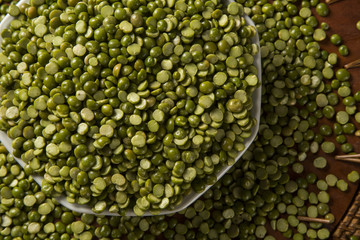 Green lentils inside a white pot on wood background. Edible raw pulses of the legume family.