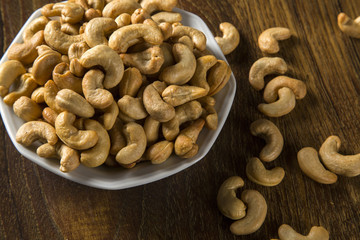 Cashew nuts in white bowl on wood background