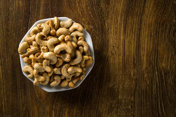 Cashew nuts in white bowl on wood background