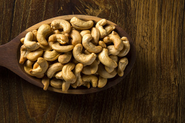 Cashew nuts in wood spoon on wood background