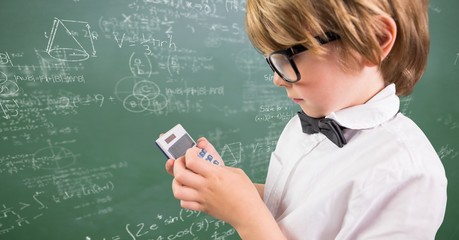 Boy with calculator against green chalkboard with math doodles