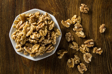 walnuts in white bowl on wood table.