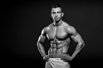 Fototapeta na wymiar Black and white photo of Muscular and fit young fitness model posing over black background.