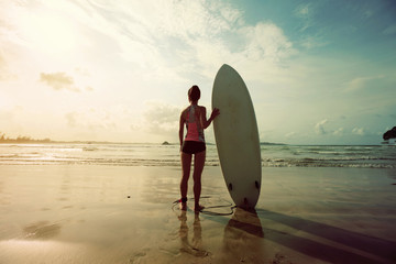 young woman surfer with surfboard on a beach