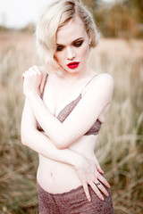 Beautiful and elegant smiling sexy blonde woman with red lips and hair waves wearing beige...