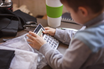 Cute little toddler boy using a calculator, figuring out a math problem, developing logic skills