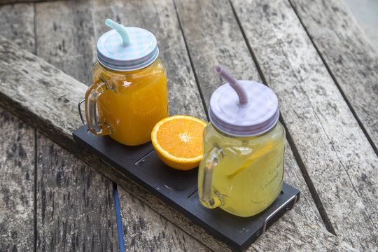 Jars of tasty fresh lemonade and orange juice on the wooden table.