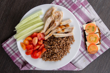 Healthy salad bowl with tomatoes, chicken on wooden background