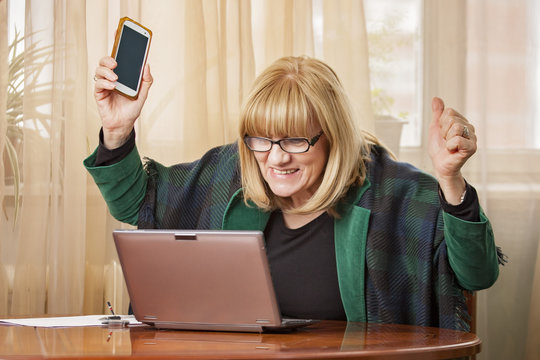 Senior blond woman cheering victoriously for receiving great news