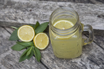 Lemon juice in jar, decorated with fresh lemons and mint leaves.