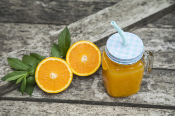Orange juice in jar, decorated with fresh oranges and mint leaves.
