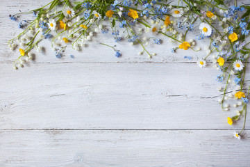 Naklejka premium Spring flowers of lilies of the valley, forget me not, daisies on a white wooden background