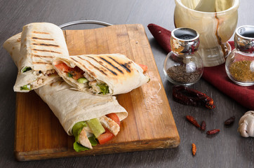 Shaurma chicken roll in a pita with fresh vegetables and cream sauce composition on wooden...