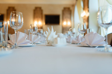 Plate with fork, knife and napkin served on the wedding table, all ready for the holiday. Table with space for taking goods in the background, blurred background under the tree. With space for text