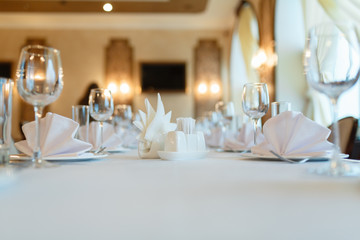 Plate with fork, knife and napkin served on the wedding table, all ready for the holiday. Table with space for taking goods in the background, blurred background under the tree. With space for text