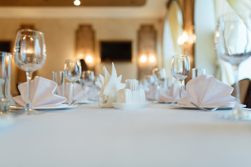 Plate with fork, knife and napkin served on the wedding table, all ready for the holiday. Table with space for taking goods in the background, blurred background under the tree. With space for text